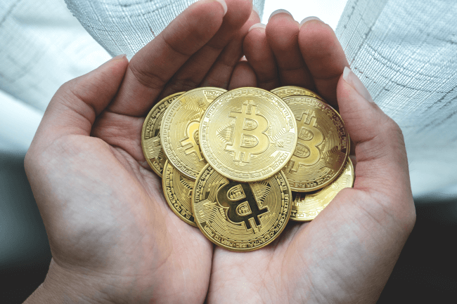 Kvinde, der holder bitcoins i hænderne